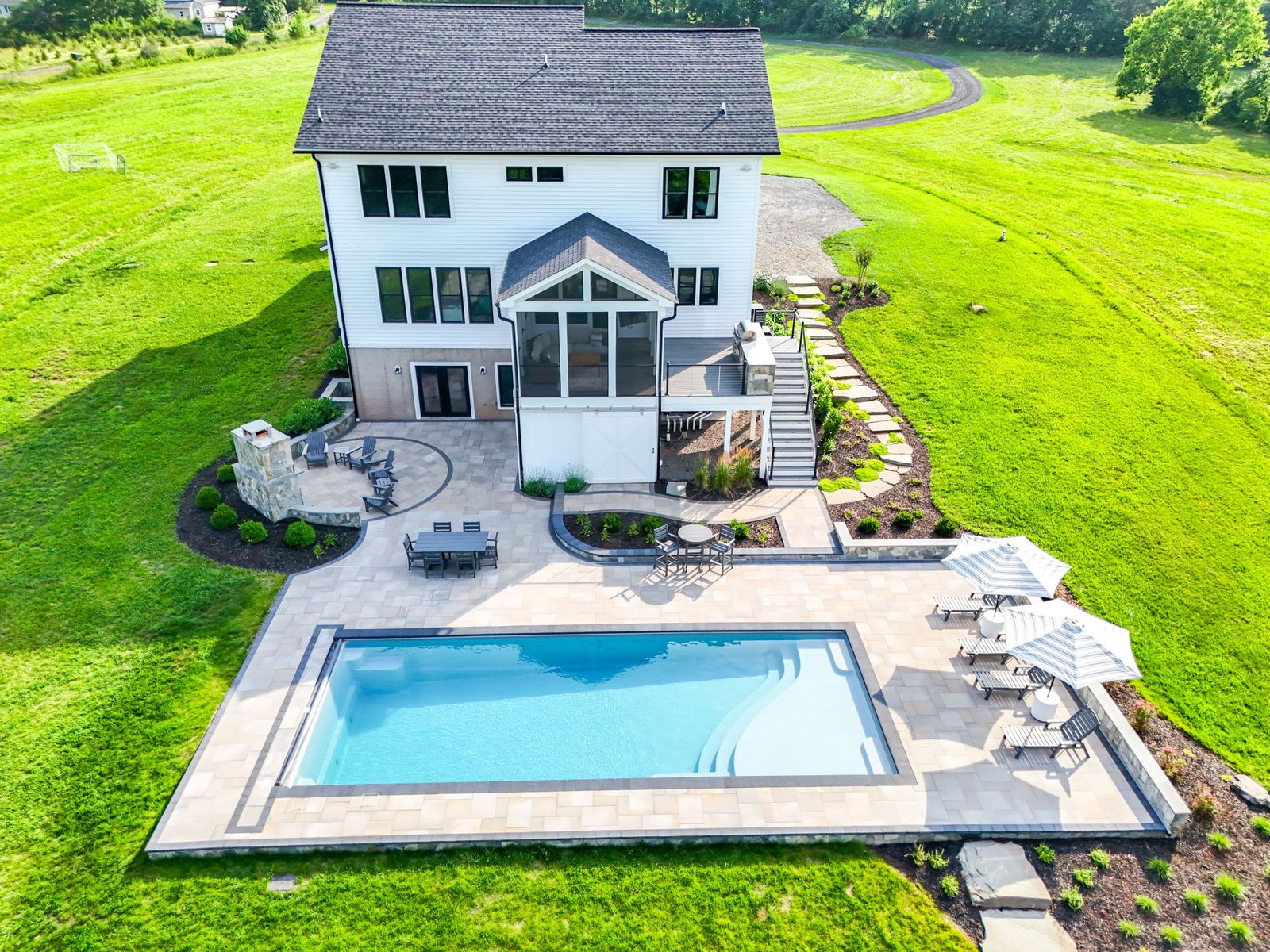 Aerial view of a fiberglass pool, paver patio, and stone outdoor fireplace built by Outdoor Solutions on a Northern Virginia acreage lot